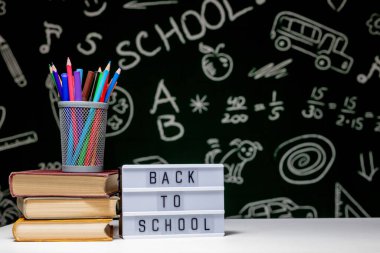 Kitap, kalem ve küre ile okul arka planına yeşil karatahta arka planında beyaz masa üzerinde