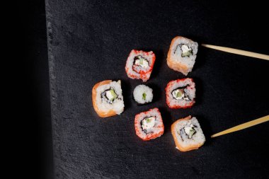 Siyah arka planda somon, peynir ve salatalıklı Philadelphia dürümü. Suşi Philadelphia.