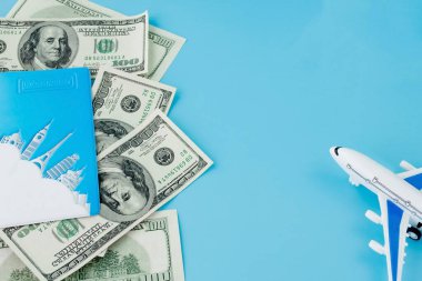 Pasaportunda yolcu uçağı modeli ve mavi arka planda dolar var. Seyahat kavramı, kopyalama alanı