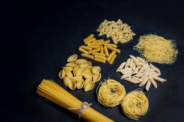 Siyah zemin üzerinde çeşitli makarna türleri. Üst Manzara. Çeşitli makarna çeşitleri. Tasarım için alanı kopyala