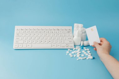 İlaç ve klavyeli alışveriş arabası oyuncağı. Haplar, su toplayan paketler, tıbbi şişeler, termometre, mavi arka planda koruyucu maske. - Evet. Sağlık ve internet alışverişi. Metniniz için en üstteki görünüm.