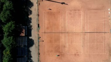 Tenis sahası yukarıdan iki adamla maç yaparken görülüyor. Olgun, çevik ve sağlıklılar. İnsansız hava aracı ile yapılan video