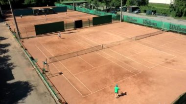 Tenis sahası yukarıdan iki adamla maç yaparken görülüyor. Olgun, çevik ve sağlıklılar. İnsansız hava aracı ile yapılan video
