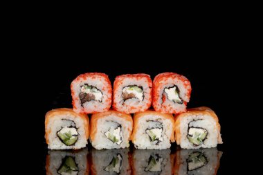 Philadelphia rulosu somon, peynir ve salatalık ile siyah arka planda yansımalı. Suşi Philadelphia.