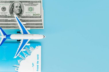 Pasaportunda yolcu uçağı modeli ve mavi arka planda dolar var. Seyahat kavramı, kopyalama alanı