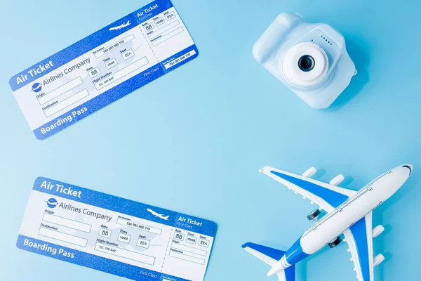 Flight tickets. camera, model of airplane and globe on blue background. Summer or vacation concept. Copy space.
