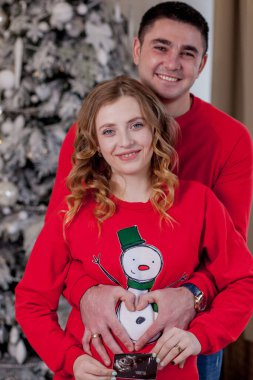 Stüdyoda hamile bir kadın ve kocası var. Hamile bir çift. Koca hamile karısına sarılıyor. Noel ve Yeni Yıl.