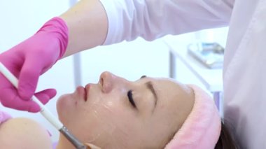 Yüz soyma maskesi, kaplıca güzellik tedavisi, cilt bakımı. Güzellik salonundaki kadın yüz bakımını alıyor, yan görüş, yakın çekim. Yaşlanma karşıtı tedavi. Kozmetoloji ve profesyonel yüz bakımı