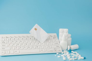 İlaç ve klavyeli alışveriş arabası oyuncağı. Haplar, su toplayan paketler, tıbbi şişeler, termometre, mavi arka planda koruyucu maske. - Evet. Sağlık ve internet alışverişi. Metniniz için en üstteki görünüm.