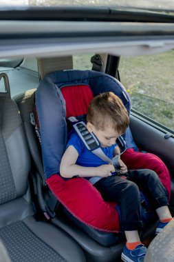 Arabanın içinde emniyet kemeri takmış küçük bir çocuk. Araç ve ulaşım kavramı.