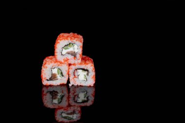 Philadelphia rulosu somon, peynir ve salatalık ile siyah arka planda yansımalı. Suşi Philadelphia.