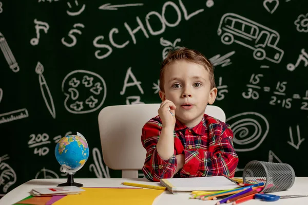 就学前の少年は学校の宿題をする 机の近くに机の上に楽しそうな表情をした小学生 教育第一 学校概念 — ストック写真