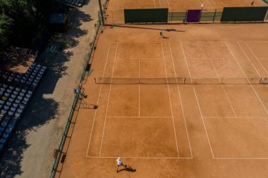 Tenis sahası yukarıdan iki adamla maç yaparken görülüyor. Olgun, çevik ve sağlıklılar. İnsansız hava aracı ile yapılan video