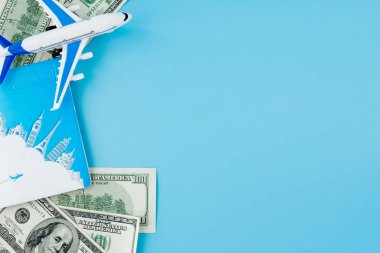 Pasaportunda yolcu uçağı modeli ve mavi arka planda dolar var. Seyahat kavramı, kopyalama alanı