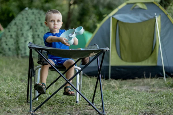 小男孩在大自然阳光下的野营场地外面吃早餐 后面有一个帐篷 — 图库照片