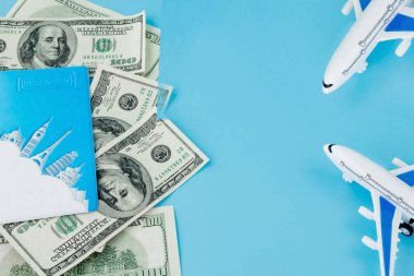 Pasaportunda yolcu uçağı modeli ve mavi arka planda dolar var. Seyahat kavramı, kopyalama alanı
