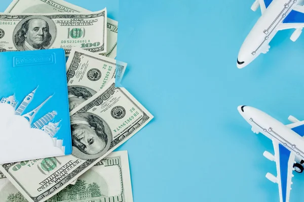 Pasaportunda yolcu uçağı modeli ve mavi arka planda dolar var. Seyahat kavramı, kopyalama alanı