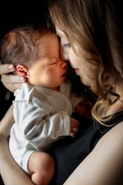 Siyah arka planda yeni doğmuş bebeğiyle güzel bir annenin portresi, kopyalama alanı. Sağlık ve tıbbi aşk yaşam tarzı anne..