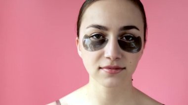 Kız gözlerinin altında siyah bantlar kullanıyor, gülümsüyor, aynanın karşısında oturuyor. Sağlıklı yaşam tarzı, gençlik, yüz bakımı