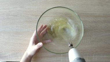 Kadın elleri yumurta beyazı kremlerini çırpıyor. Tahta masadaki karıştırıcıyla. Adım adım Belçika Waffle kurabiyeleri üst görünümü.