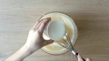 Kadın elleri yumurta beyazı kremlerini çırpıyor. Tahta masadaki karıştırıcıyla. Adım adım Belçika Waffle kurabiyeleri üst görünümü.