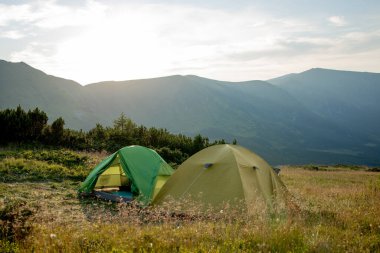Gün doğumunda ya da günbatımında dağlardaki turistik çadır manzarası. Kamp geçmişi. Macera seyahati aktif yaşam tarzı özgürlük kavramı. Yaz tatili