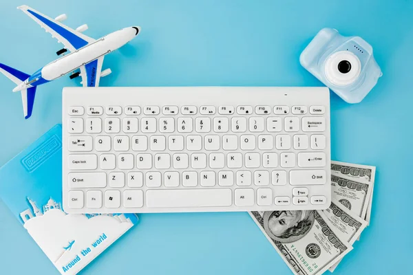 Uçak bileti rezervasyonu ve arama uluslararası seyahat konsepti, klavye, pasaport, dolar ve mavi arka planda uçak. Yaz ya da tatil konsepti. Boşluğu kopyala