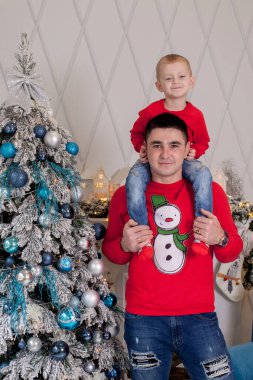 Noel ağacını Noel baloları ve hafif çelenklerle süsleyen mutlu baba ve oğul kış tatillerini kutlamaya hazırlanıyor: Mutlu Noeller ve mutlu yeni yıl 2021. Aile kavramı.