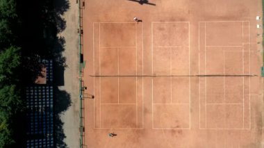 Tenis sahası yukarıdan iki adamla maç yaparken görülüyor. Olgun, çevik ve sağlıklılar. İnsansız hava aracı ile yapılan video