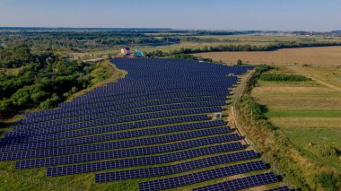 Güneşli bir günde, Yeşil Alan 'daki güneş enerjisi istasyonu. Hava görüntüsü. Güneş Panelleri Güç Üretimi Alanında Bir Satırda Duruyor. İnsansız hava aracı Güneş Çiftliği üzerinde uçuyor. Yenilenebilir yeşil enerji. Alternatif enerji kaynakları