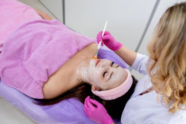 Yüz soyma maskesi, kaplıca güzellik tedavisi, cilt bakımı. Güzellik salonundaki kadın yüz bakımını alıyor, yan görüş, yakın çekim. Yaşlanma karşıtı tedavi. Kozmetoloji ve profesyonel yüz bakımı