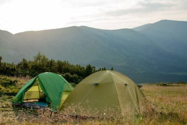 Gün doğumunda ya da günbatımında dağlardaki turistik çadır manzarası. Kamp geçmişi. Macera seyahati aktif yaşam tarzı özgürlük kavramı. Yaz tatili