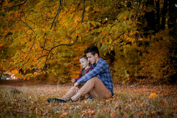 Mutlu aile sonbahar parkında eğleniyor. Baba ve oğul sarı bulanık yapraklara karşı. Mutlu aile kavramı, Babalar Günü..