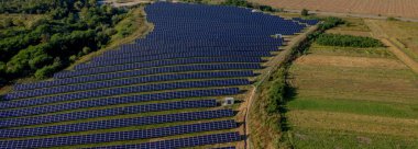 Güneşli bir günde, Yeşil Alan 'daki güneş enerjisi istasyonu. Hava görüntüsü. Güneş Panelleri Güç Üretimi Alanında Bir Satırda Duruyor. İnsansız hava aracı Güneş Çiftliği üzerinde uçuyor. Yenilenebilir yeşil enerji. Alternatif enerji kaynakları