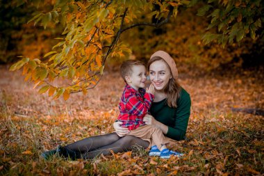 Mutlu genç anne parkta güneş ışığı altında oynayıp, oğluyla eğleniyor. Mutlu aile kavramı, Anneler Günü. .