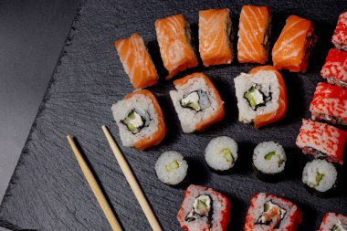 Siyah arkaplanda suşi rulosu. Philadelphia balık, Japon somonu. Lezzetli suşi, pirinç, salatalık, geleneksel wasabi taze, sağlıklı, çiğ gurme..