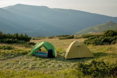 Gün doğumunda ya da günbatımında dağlardaki turistik çadır manzarası. Kamp geçmişi. Macera seyahati aktif yaşam tarzı özgürlük kavramı. Yaz tatili