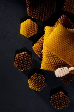 Bal geçmişi. Doğal bal tarağı ve tahta kaşık. Siyah kırsal masada.