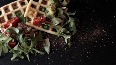 Yemek manzarası hazırlıyorum. Sunum taze pişmiş Belçika waffleları roka, domates ve siyah bir tabakta avokado. Lezzetli waffle. Kahvaltı konsepti