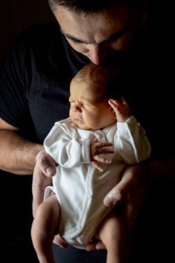 Babası 15 günlük oğlunu siyah arka planda tutuyordu..
