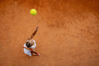 Güneşli bir günde kil tenis kortunda tenis oynayan profesyonel bir tenisçi.