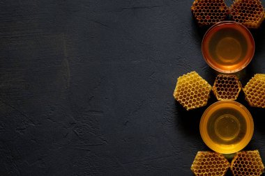 Kavanozda bal ve bal peteği. Siyah tahta bir arka planda. Metin için boş alan. Üst görünüm.
