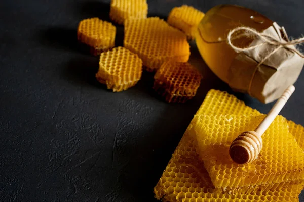 Méz egy üvegben és egy méhsejt. Fekete fából készült háttérrel. Szabad hely a szövegnek. Felülnézet. — Stock Fotó