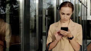 Yetişkin Kafkasyalı Kendine güvenen Genç İş Kadını Modern Ofis Binası 'nın dışında telefonla konuşuyor.
