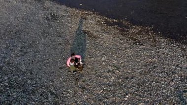 Ukrayna, Kyiv - 19 Aralık 2019: Oğluyla birlikte genç bir kadın nehirdeki bir çöp torbasında plastik çöp topluyor. Kullanılmış kirli plastik şişeler. Çevre kirliliği kıyısı.