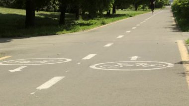 Bisiklet işaretleri parktaki yolda, arka planda koşan kadın.
