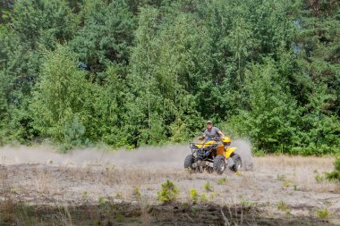 Kyiv - Eylül 2019 Adam kumlu bir ormanda sarı bir ATV ile arazi aracına biniyor. Ekstrem spor hareketleri, macera, turistik eğlence