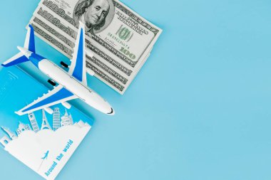 Pasaportunda yolcu uçağı modeli ve mavi arka planda dolar var. Seyahat kavramı, kopyalama alanı