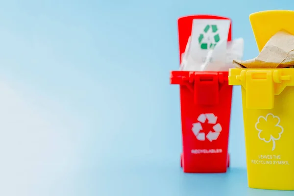 青色の背景にリサイクルシンボルを持つ黄色 赤のごみ箱 街を整頓し リサイクルのシンボルを残します 自然保護の概念 — ストック写真