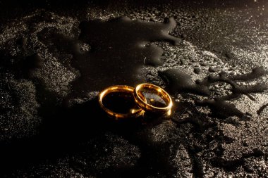 Siyah arka planda iki altın alyans